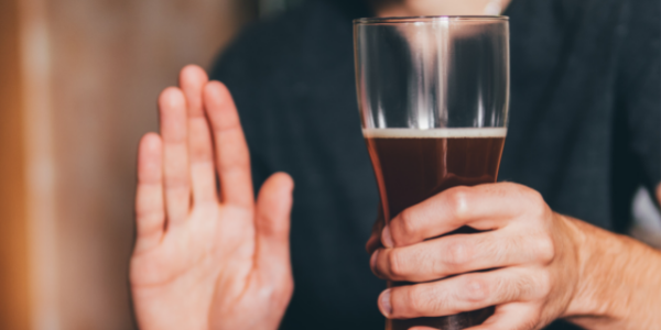 man holding beer with one hand up to indicate stop