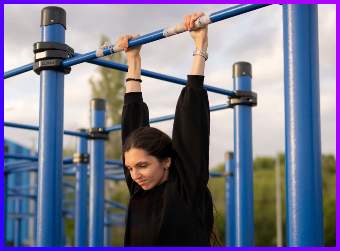 Person taking part in the Hold on Challenge outside on a blue bar