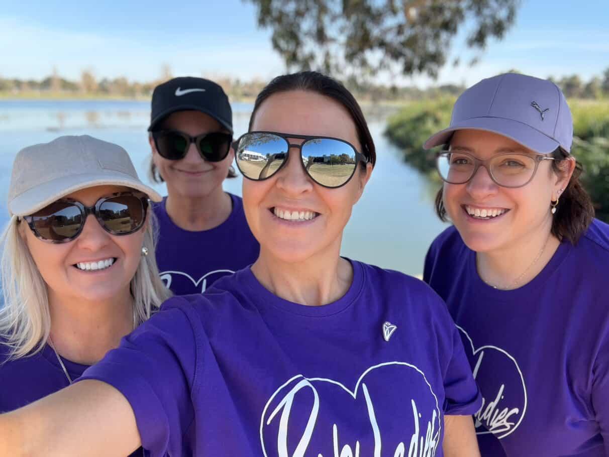 Image of four women taking a selfie, all wearing matching purple t-shirts