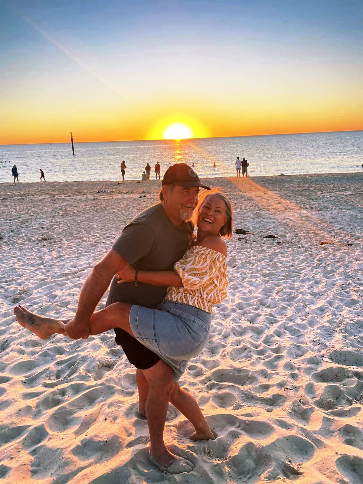 Wendy and her husband dancing on a beach at sunset